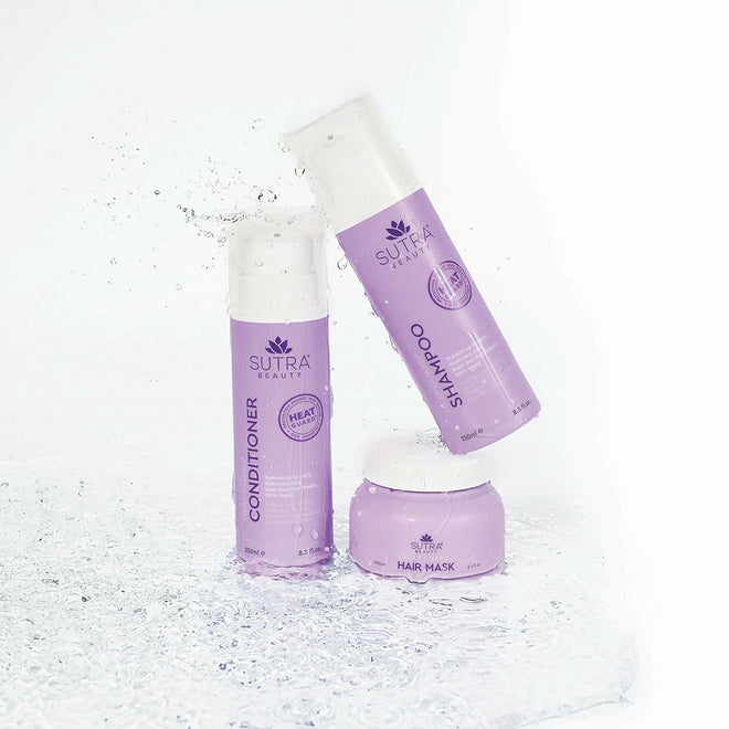 Sutra heat guard products - conditioner, shampoo, and hair mask - in light purple packaging, placed on a white floor with water  around