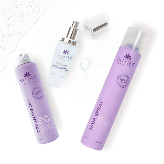 Sutra heat guard products - dry shampoo, hair serum, and hair spray - in light purple packaging, placed on a white floor with water 